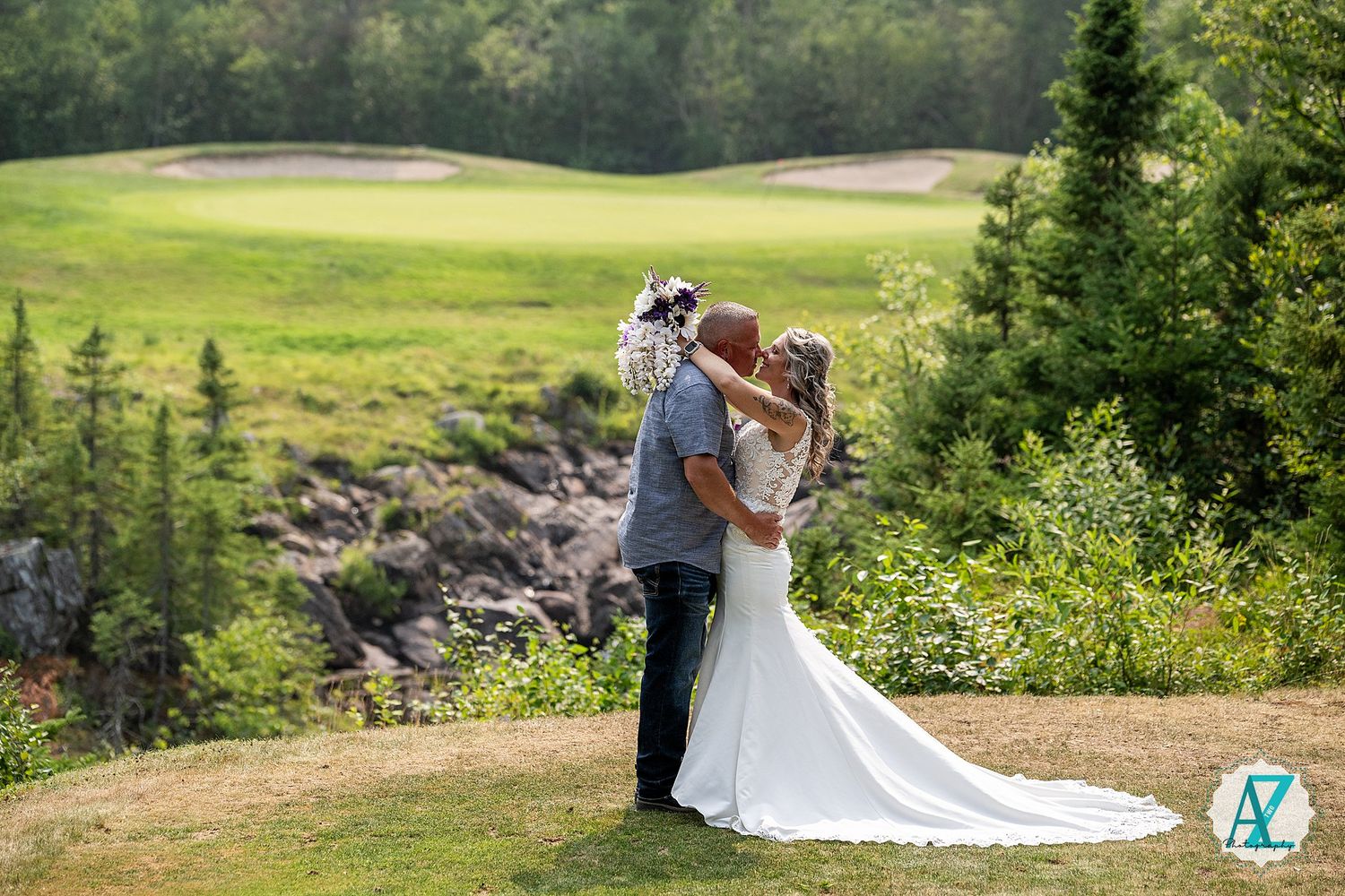 A romantic newlywed couple embraces on a scenic golf course surrounded by evergreen trees and rolling hills.