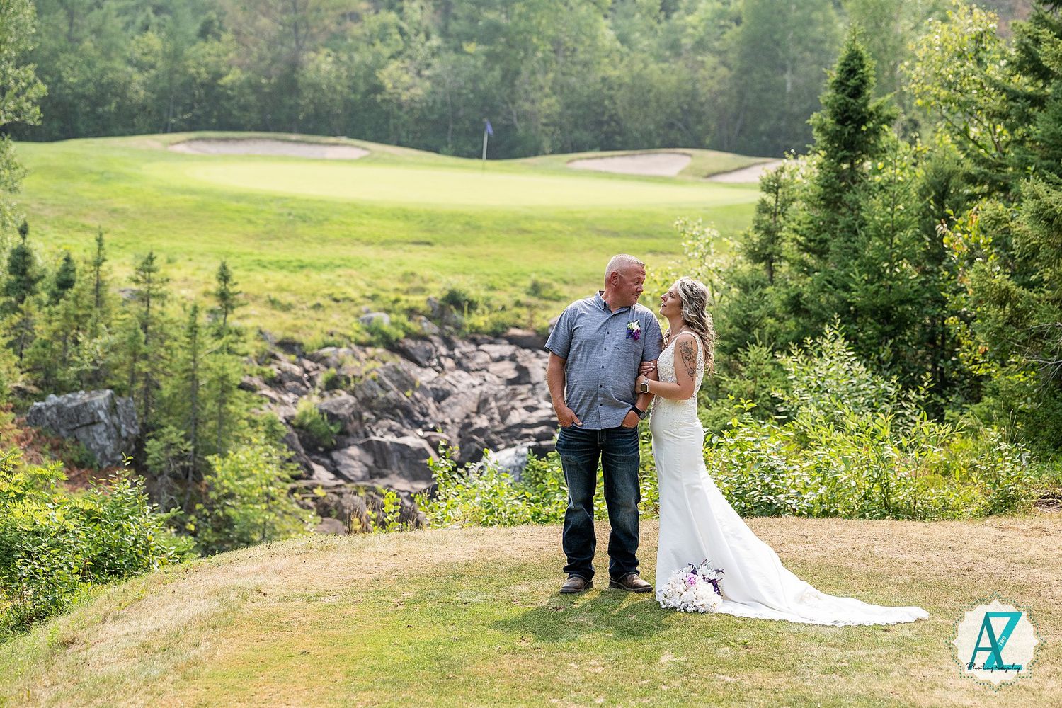 A scenic outdoor wedding celebration takes place on a lush green golf course surrounded by evergreen trees and mountains.