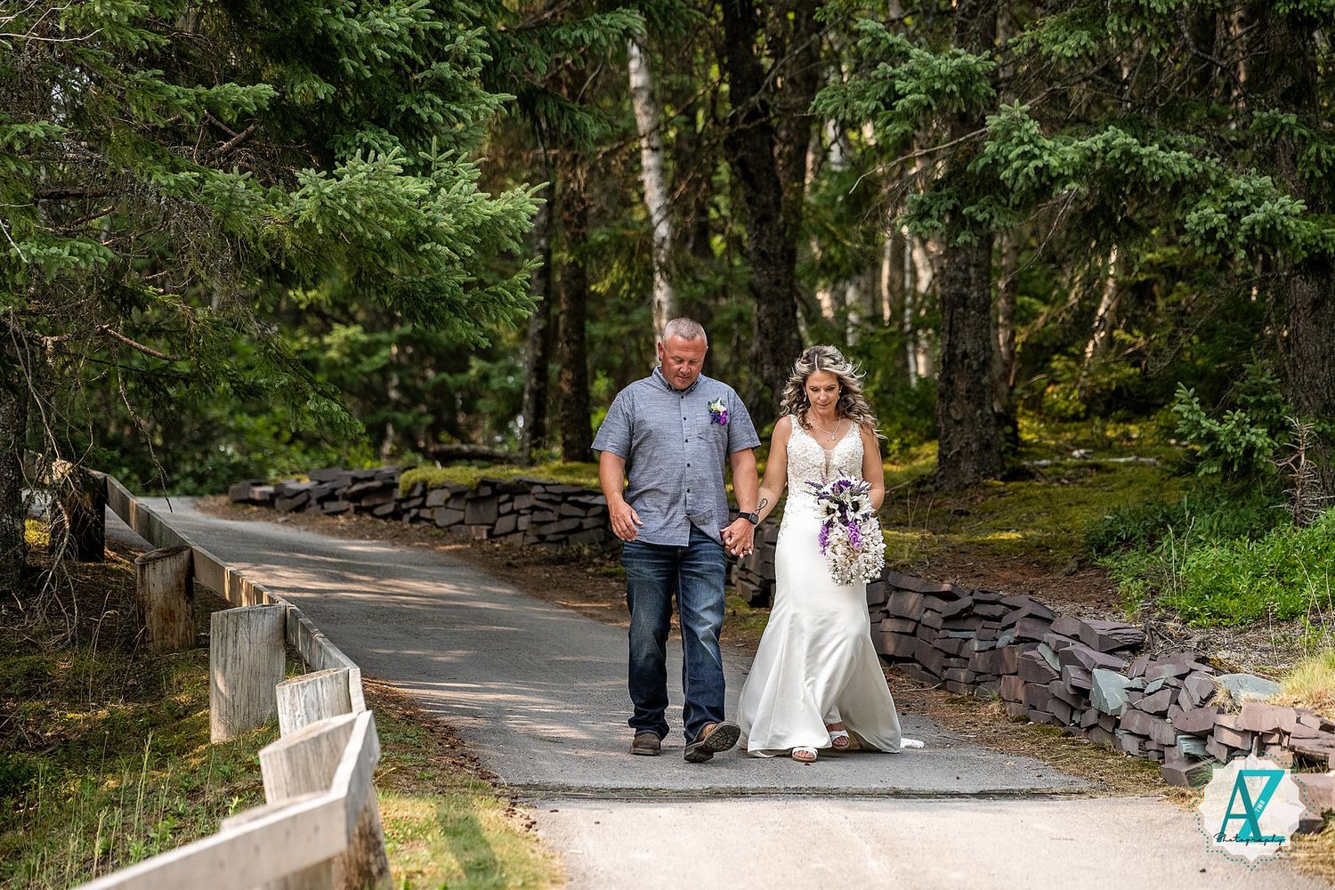 A couple walks hand in hand along a curved garden path surrounded by lush greenery and stone walls.