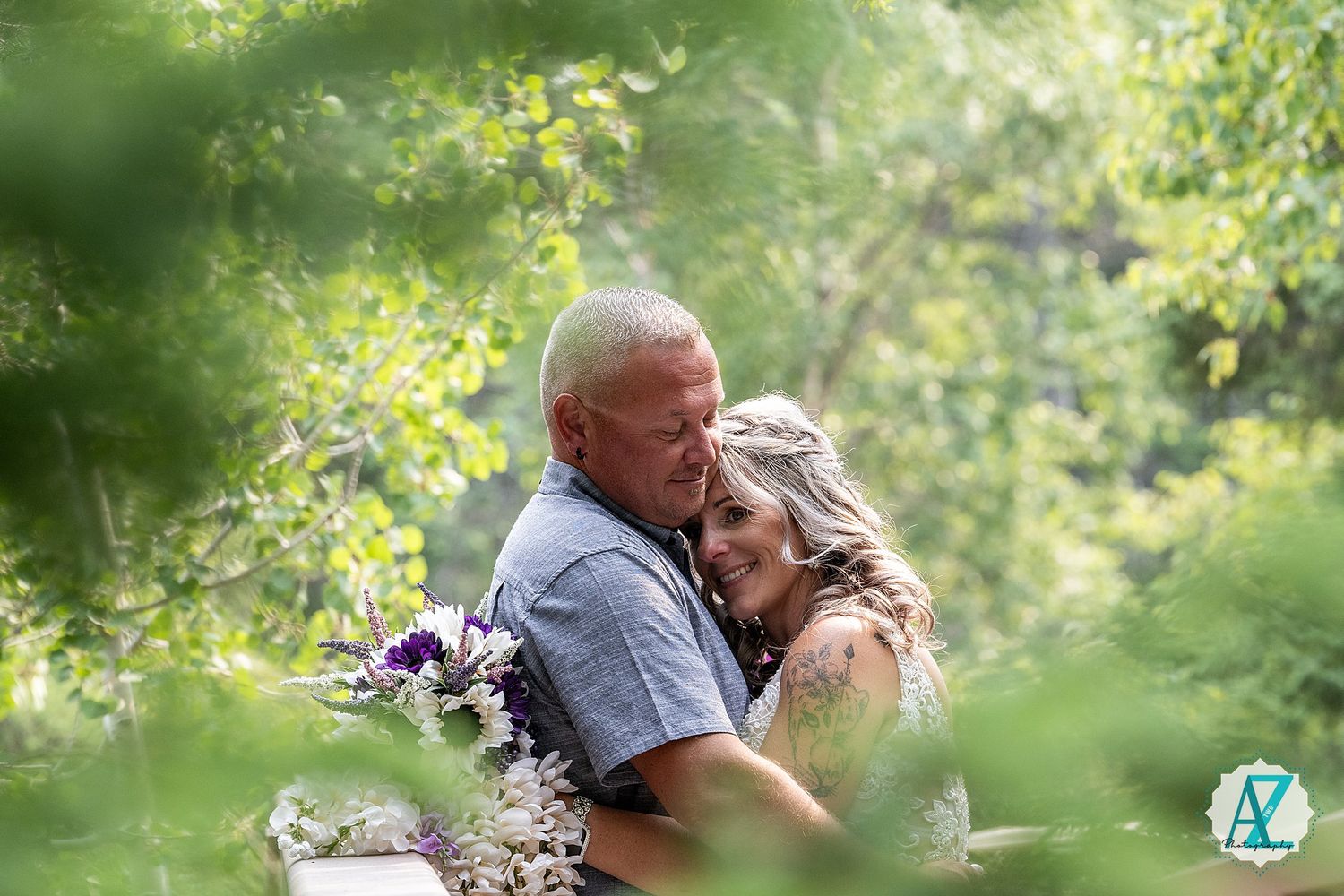 Two people embrace in a romantic moment surrounded by lush green foliage in an outdoor garden setting.