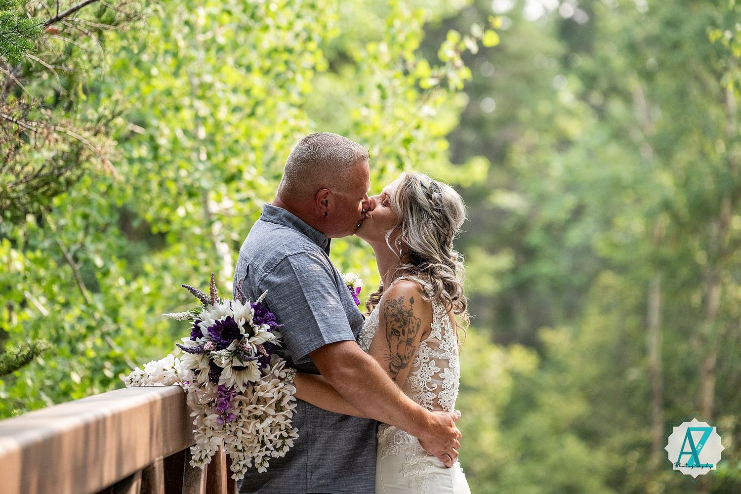 A romantic couple embraces on a wooden deck in a lush garden setting with soft sunlight filtering through trees.