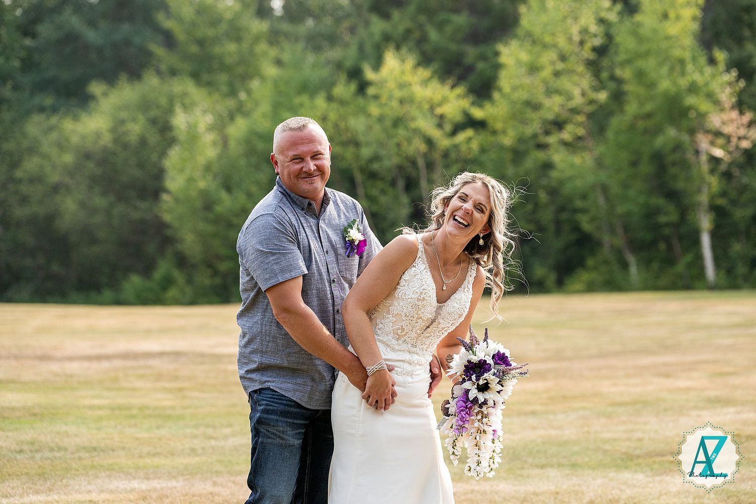 A couple dances and laughs together in a sunny meadow during a romantic outdoor photo session.