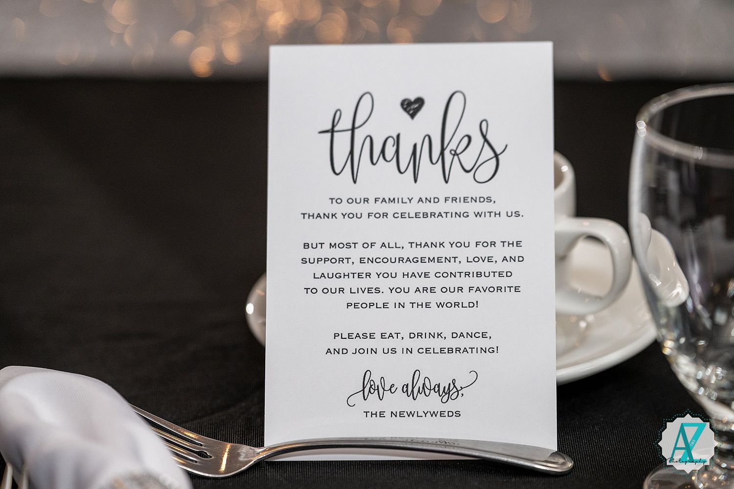 Wedding thank you cards with elegant calligraphy displayed against a dark background with bokeh effects.