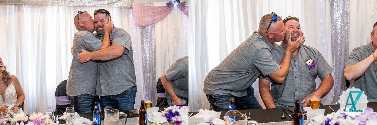Two people share emotional embraces at a wedding reception table decorated with purple flowers and white linens.