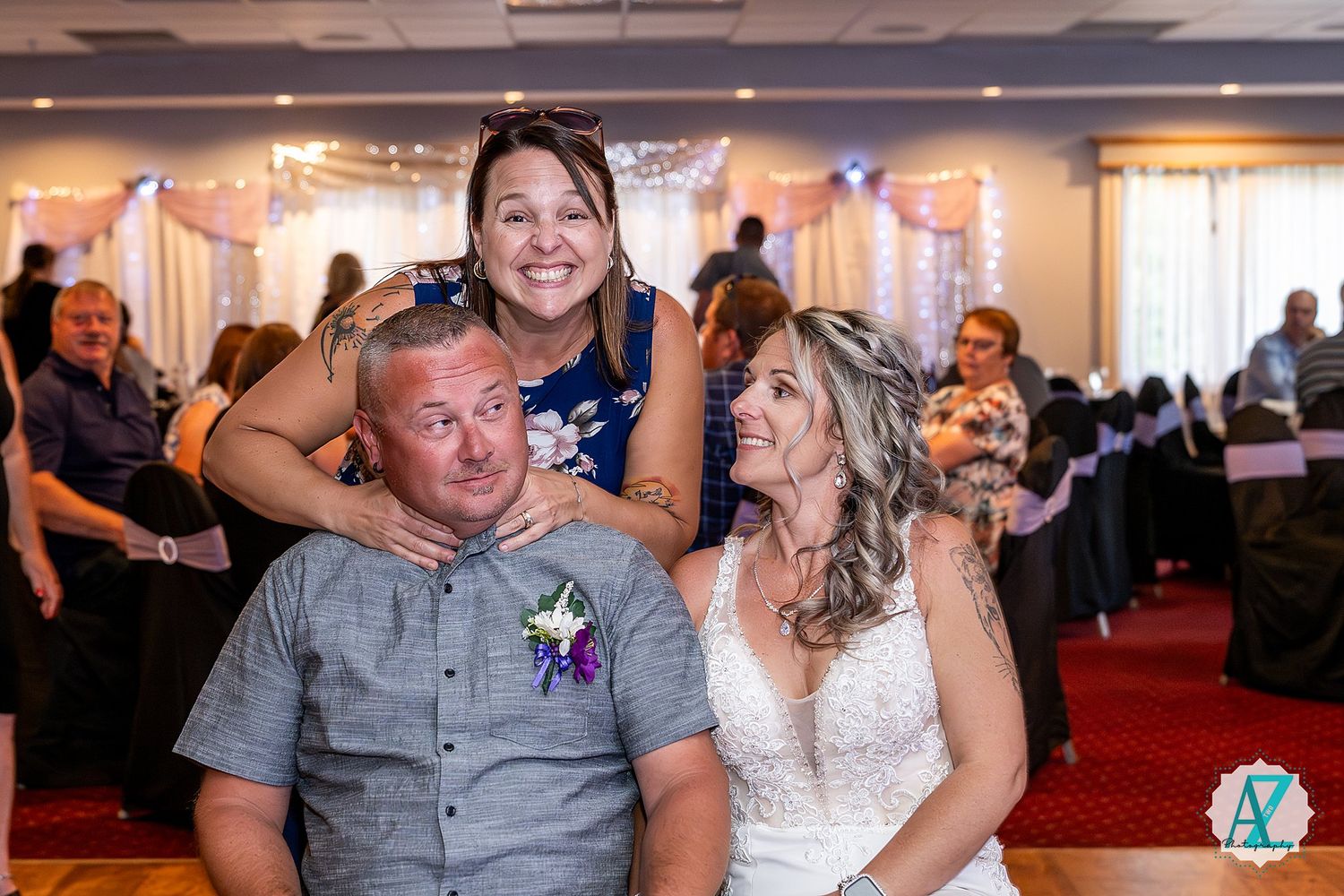 Wedding guests dance and celebrate together during a reception in a brightly lit banquet hall.
