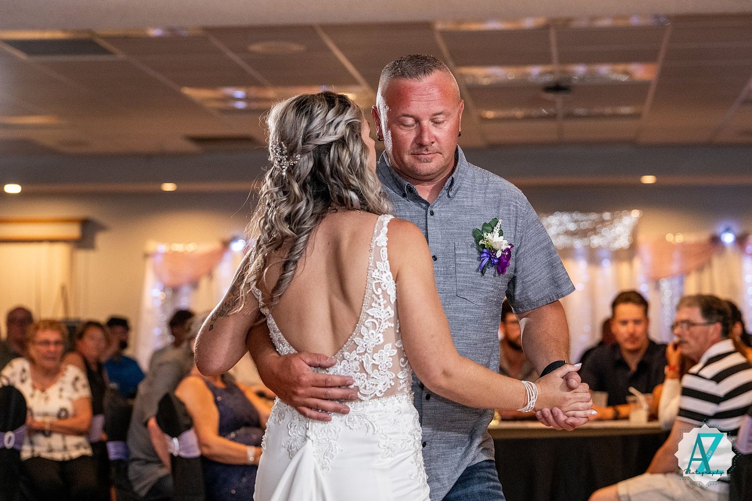 A tender moment at a wedding reception as two people share a dance together in a venue with soft lighting.
