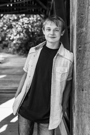 Black and white portrait series showing casual poses against wooden beams in outdoor setting.