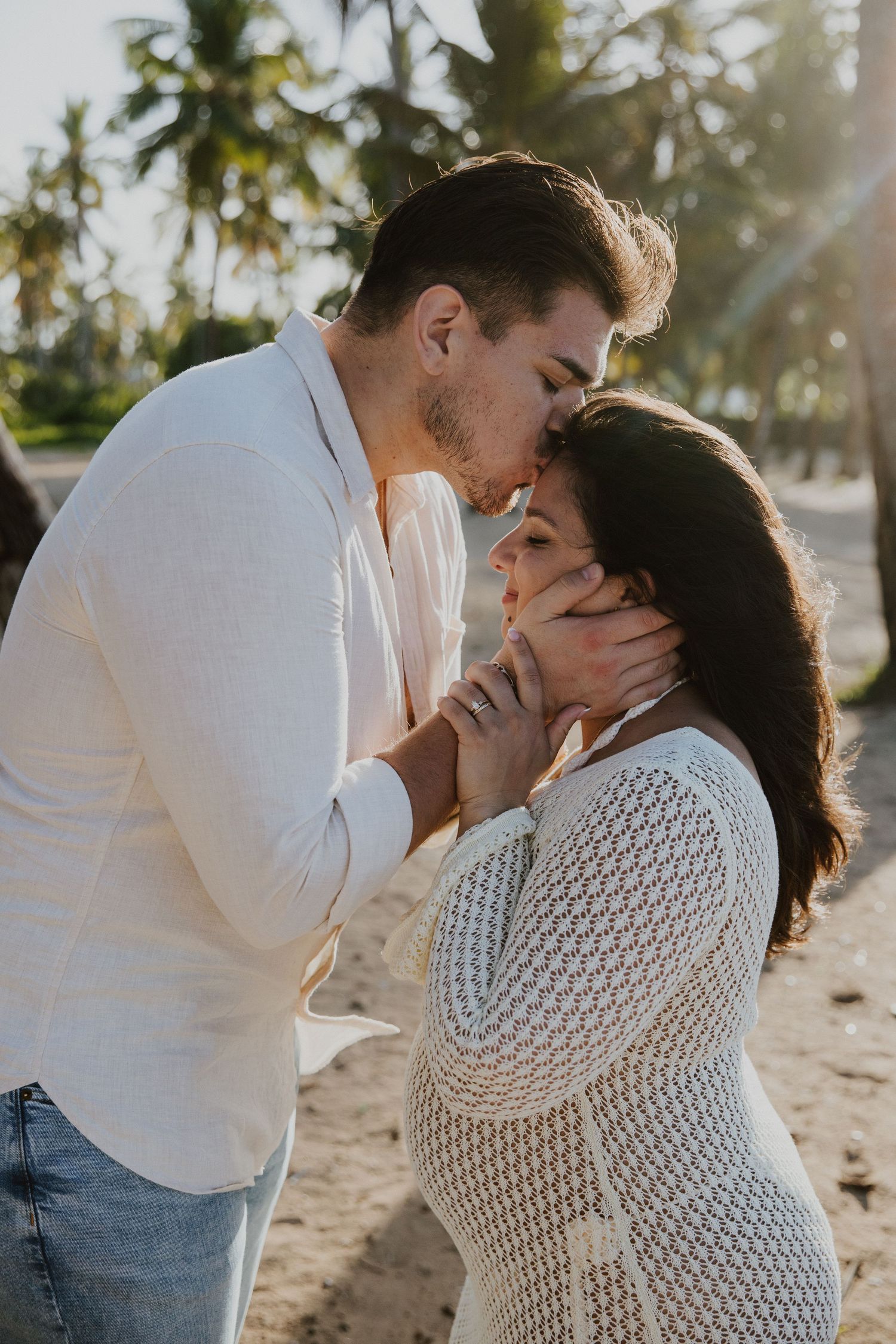 An intimate moment between a couple on a tropical beach with palm trees.