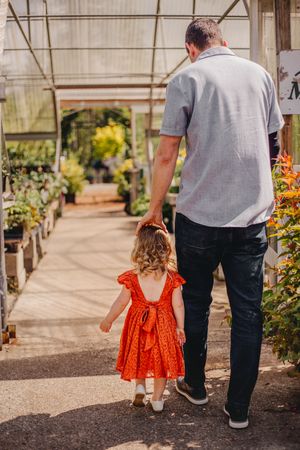 Father and child walking together during their greenhouse photoshoot at Christianson Nursery near Seattle WA