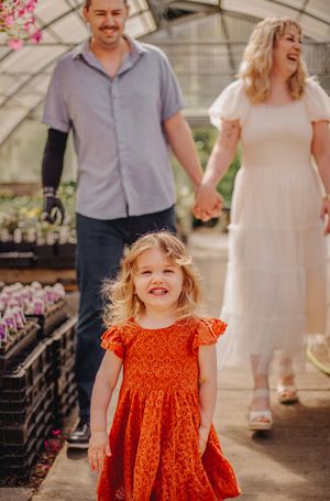 Mother, father and child walking together during their greenhouse photoshoot at Christianson Nursery near Seattle WA
