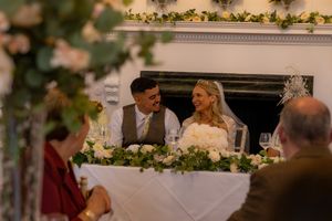 Wedding reception tables decorated with floral arrangements and candlelight in an elegant indoor venue.