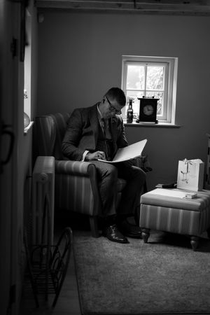 A series of black and white photos showing a groom getting ready in a dimly lit room.