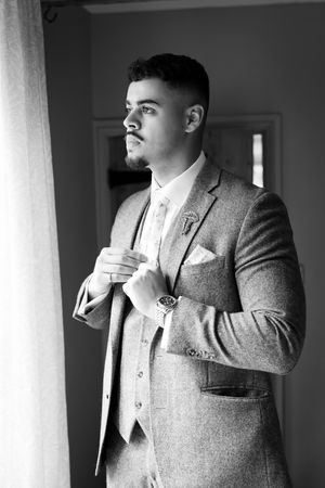 A series of black and white photos showing someone adjusting their grey tweed suit jacket and tie.