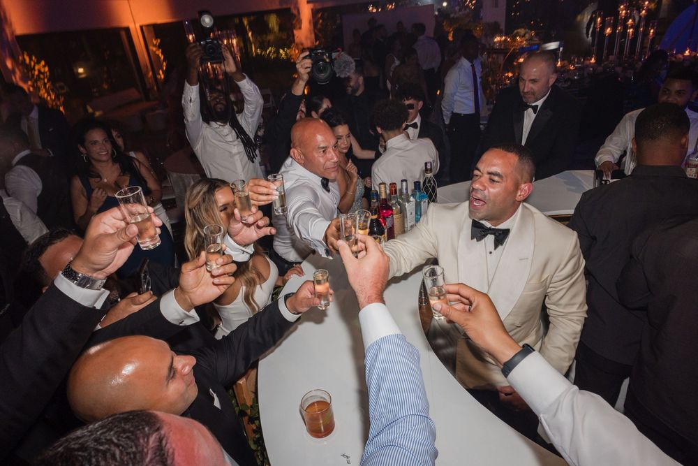 A lively celebration at a dimly lit venue with people raising glasses in a toast during what appears to be a party or reception.