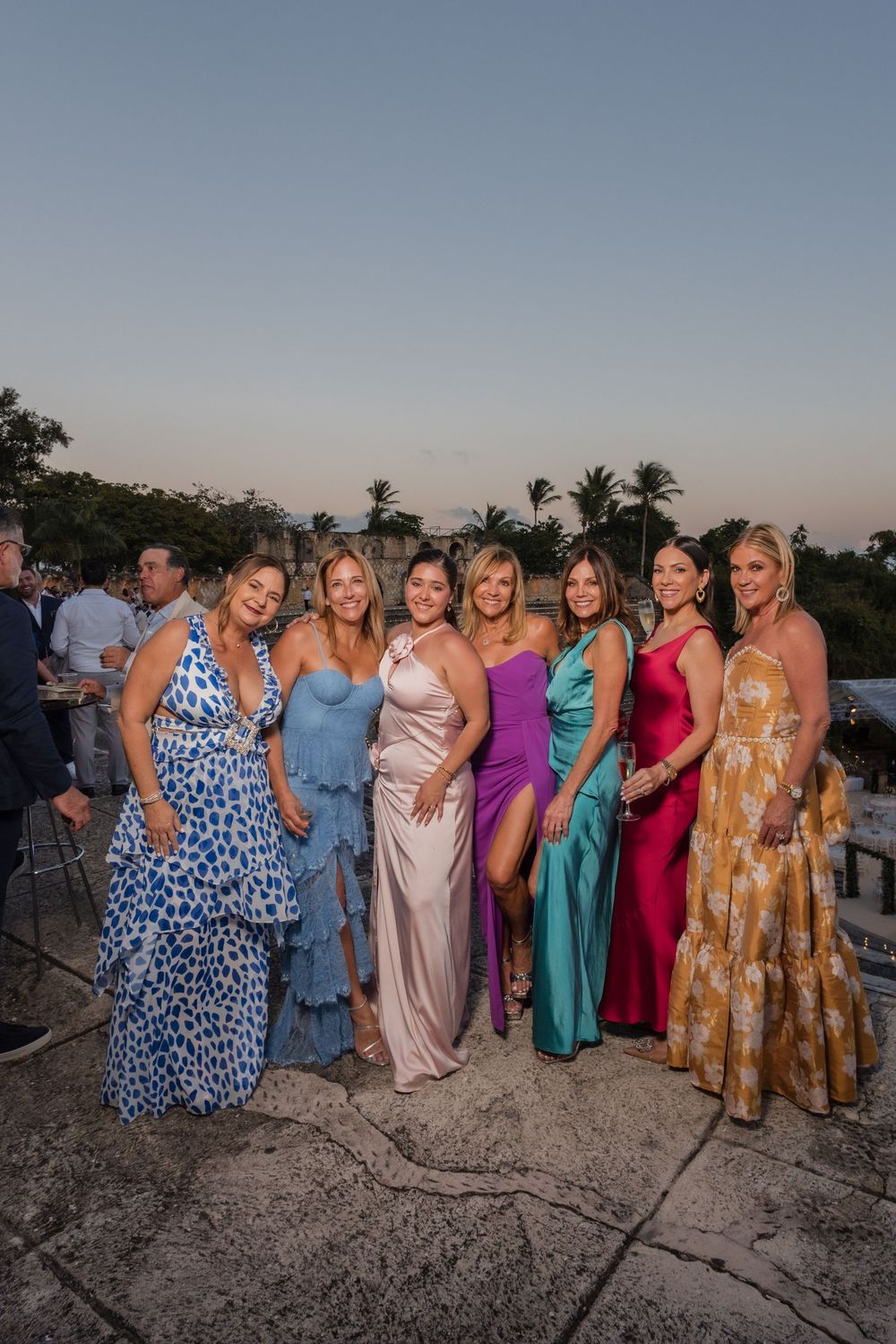 A group poses together at sunset wearing colorful formal dresses in various styles and hues.