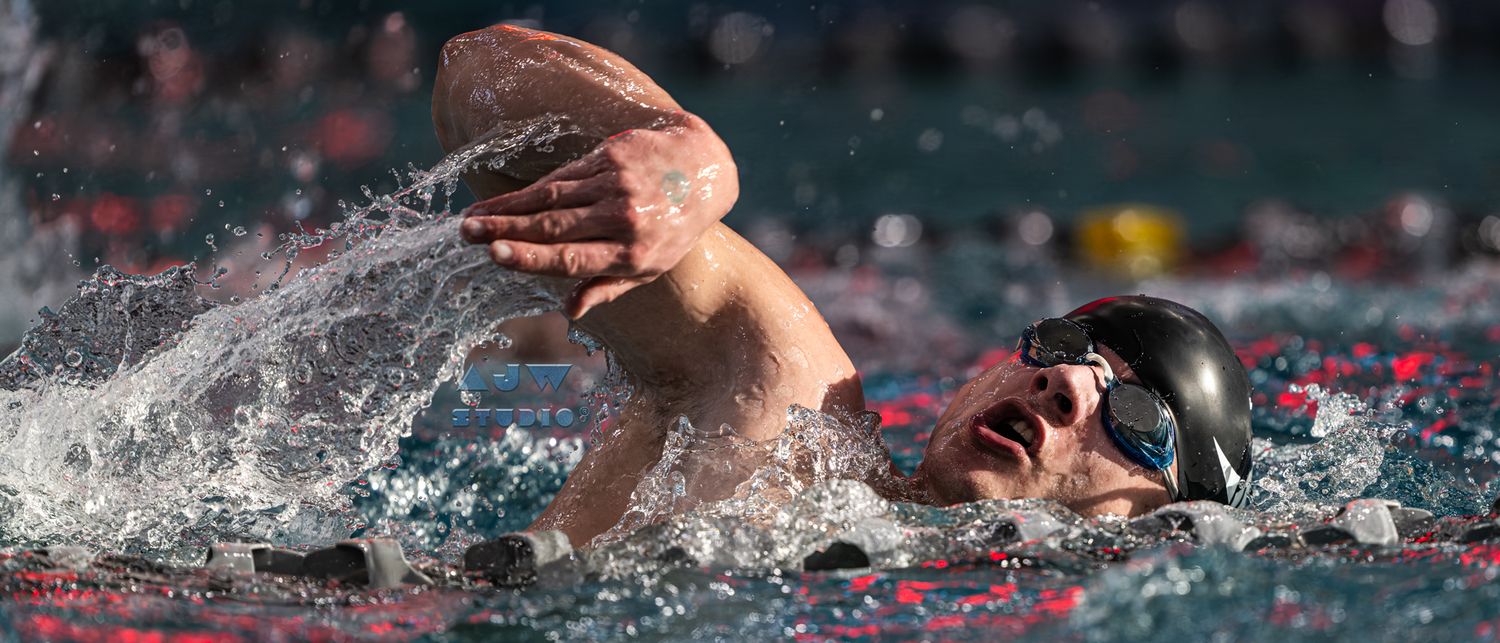 Competitive swimmer performs freestyle stroke during a race in a swimming pool.