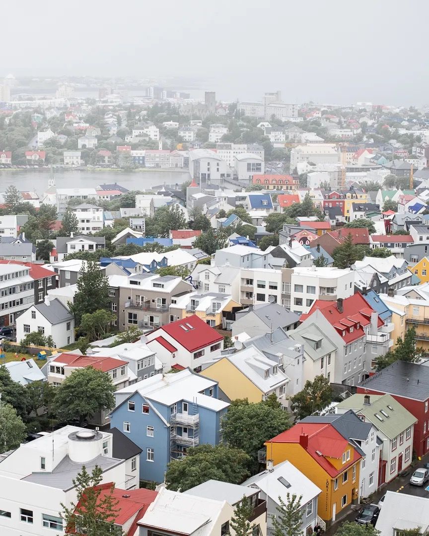 Foggy aerial view of a city with rows of colourful houses and soft light.