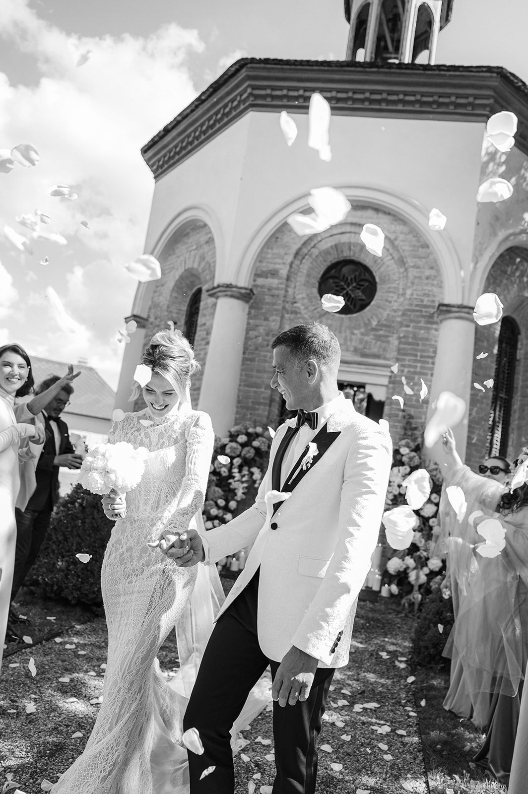 Celebratory outdoor wedding scene with confetti and joyful guests at a church entrance.