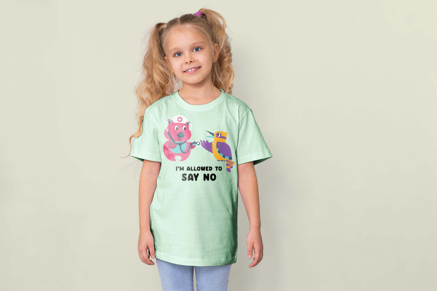 A child wearing a mint green t-shirt with a cute cartoon design stands against a light background.