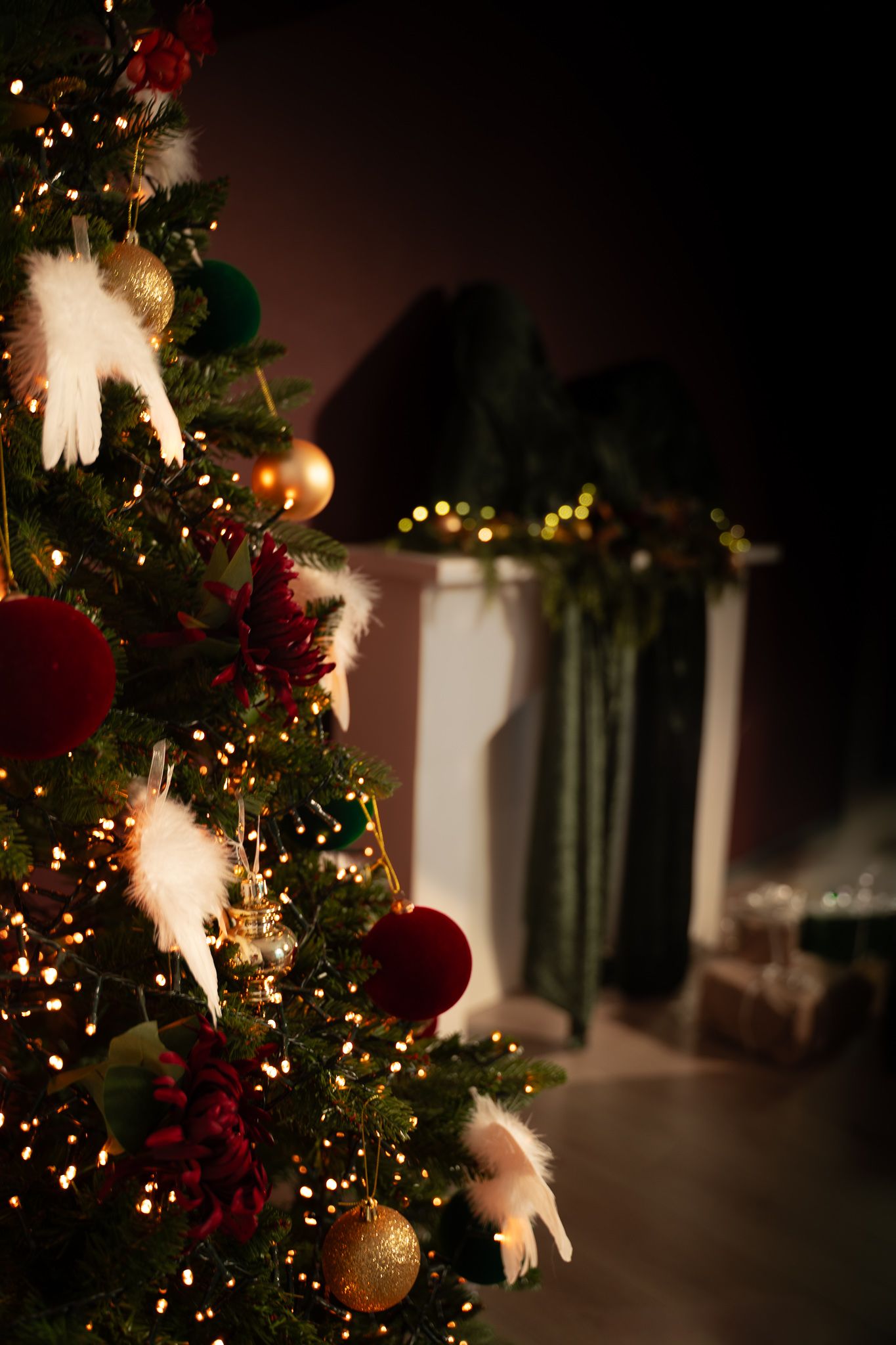 Decorated Christmas tree with red ornaments and white lights creates a warm holiday ambiance in a dimly lit room.
