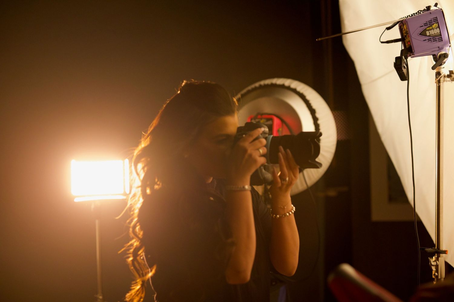 A dramatic lighting setup with multiple studio lights and equipment silhouetted against a dark background.