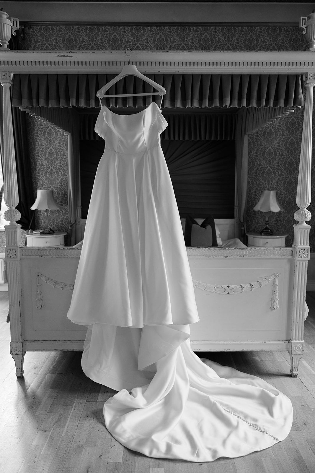 A flowing white wedding dress with a long cathedral train is elegantly displayed in a luxurious room.