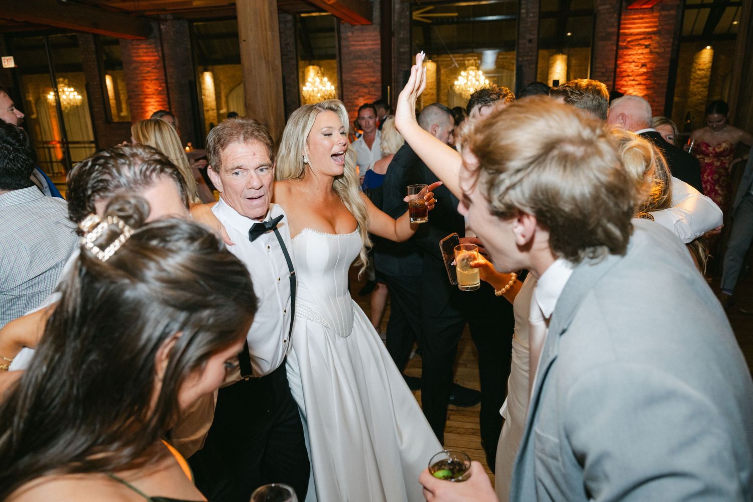 A lively dance party scene with people celebrating in a dimly lit venue with orange ambient lighting.