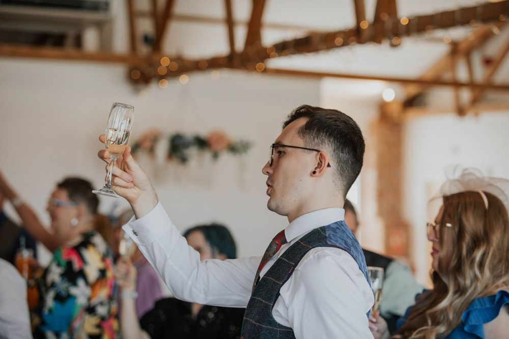 Wedding guest raises champagne glass for a toast during elegant wedding reception celebration.