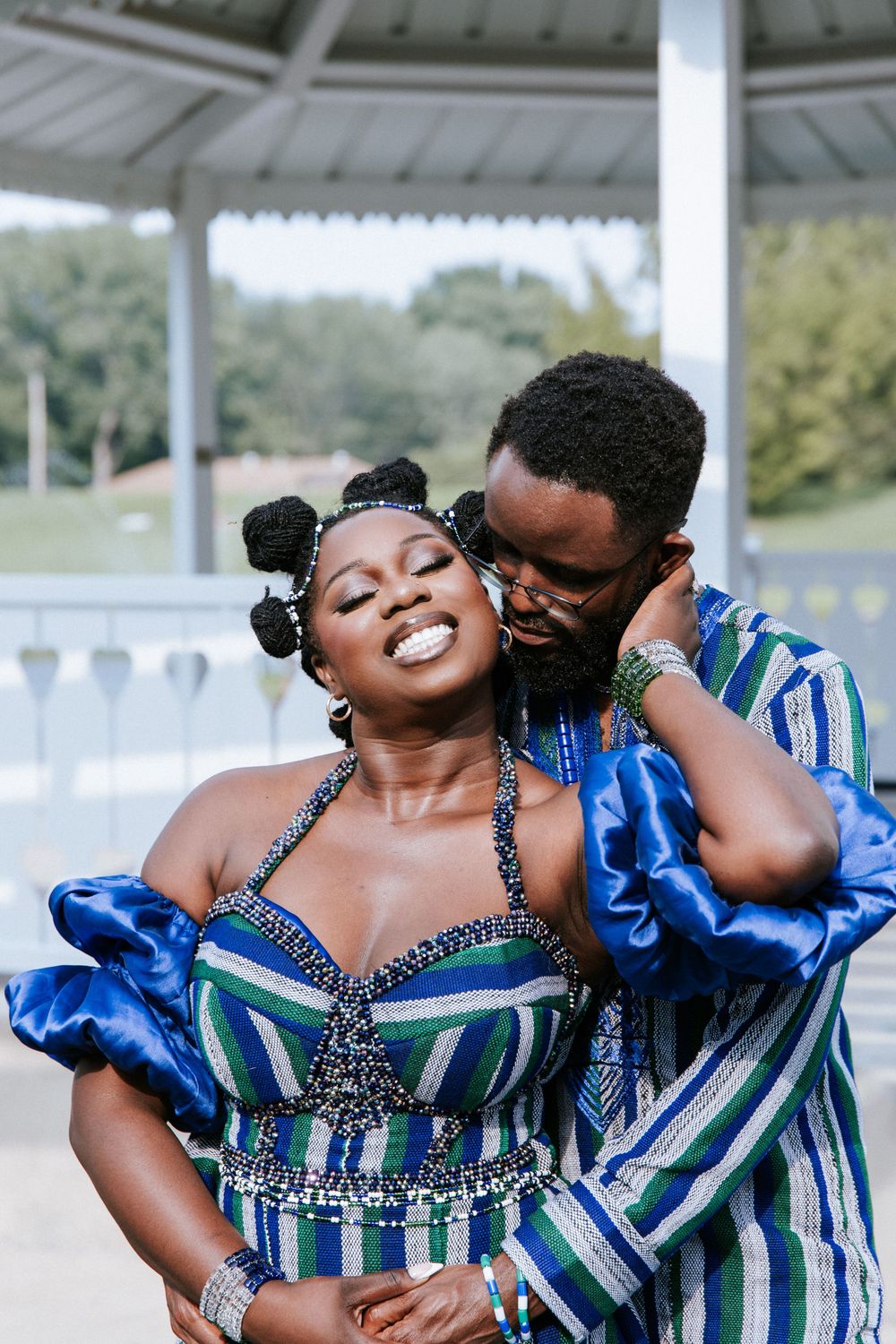 A couple in coordinated blue and striped outfits share joyful moments during a romantic outdoor photoshoot.