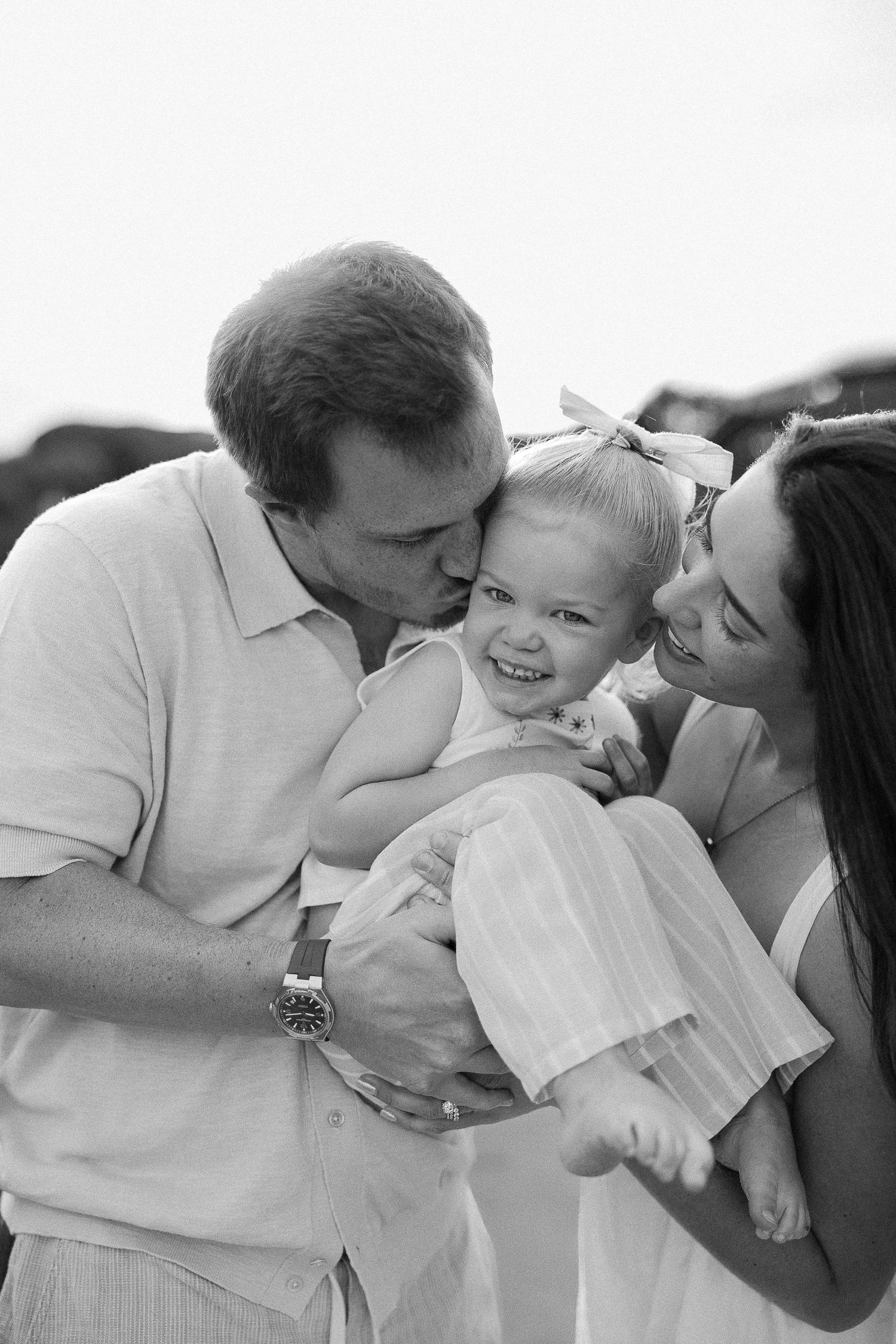 Candid family beach portraits at Crystal Cove with toddler laughing