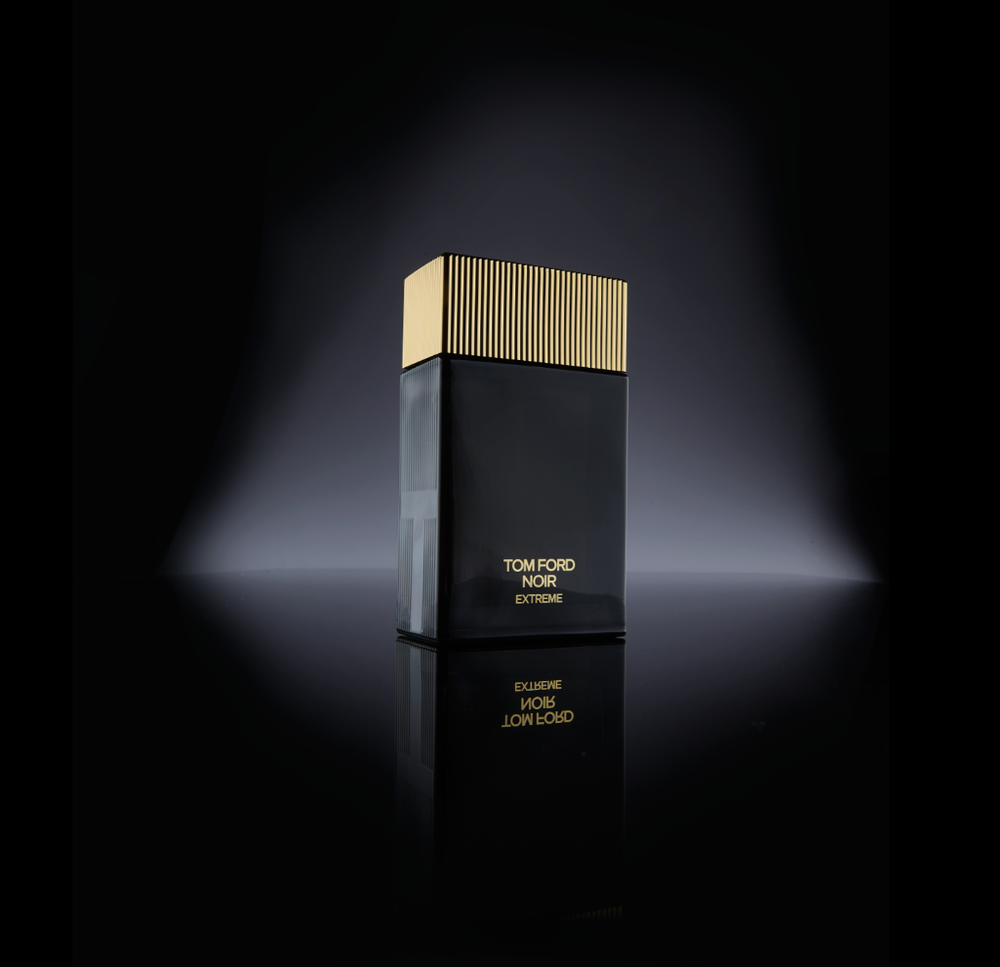 Black luxury cosmetic packaging with subtle spotlight effect against dark background.