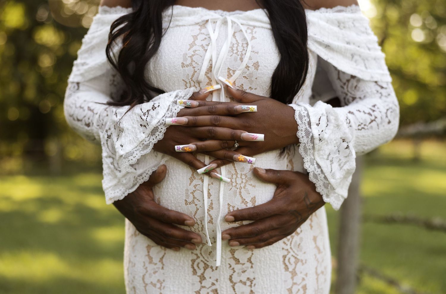 Intimate maternity portraits showing loving embrace in sunlit outdoor setting.