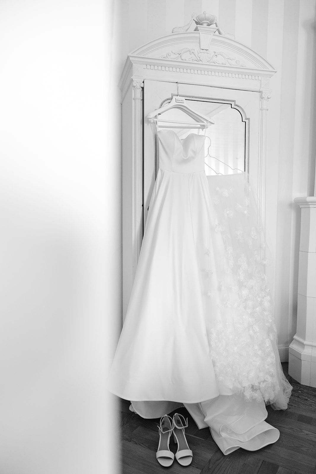 A row of elegant white wedding dresses and bridal shoes displayed against a light-colored wall.