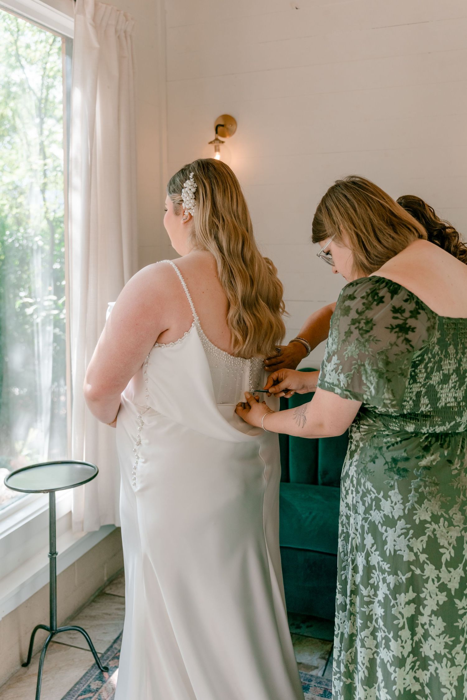 A sequence of wedding preparation photos showing bridesmaids helping with final dress adjustments in a bright room.