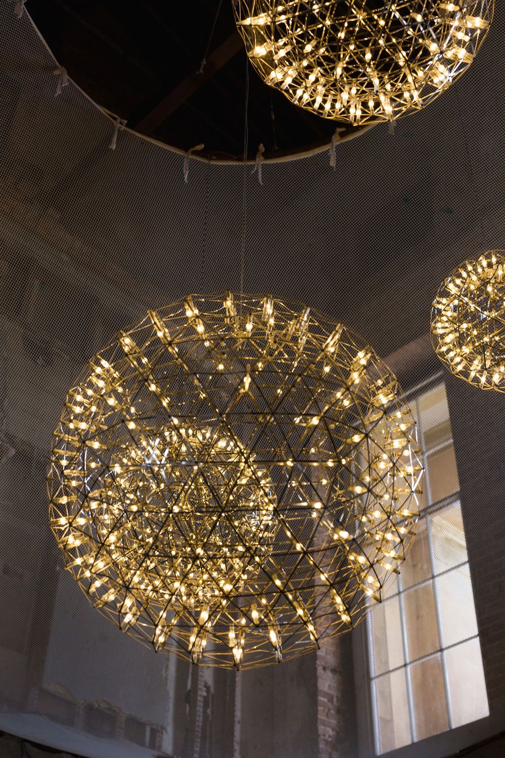 Modern circular chandeliers with intricate LED lights create a stunning geometric display against a white ceiling.