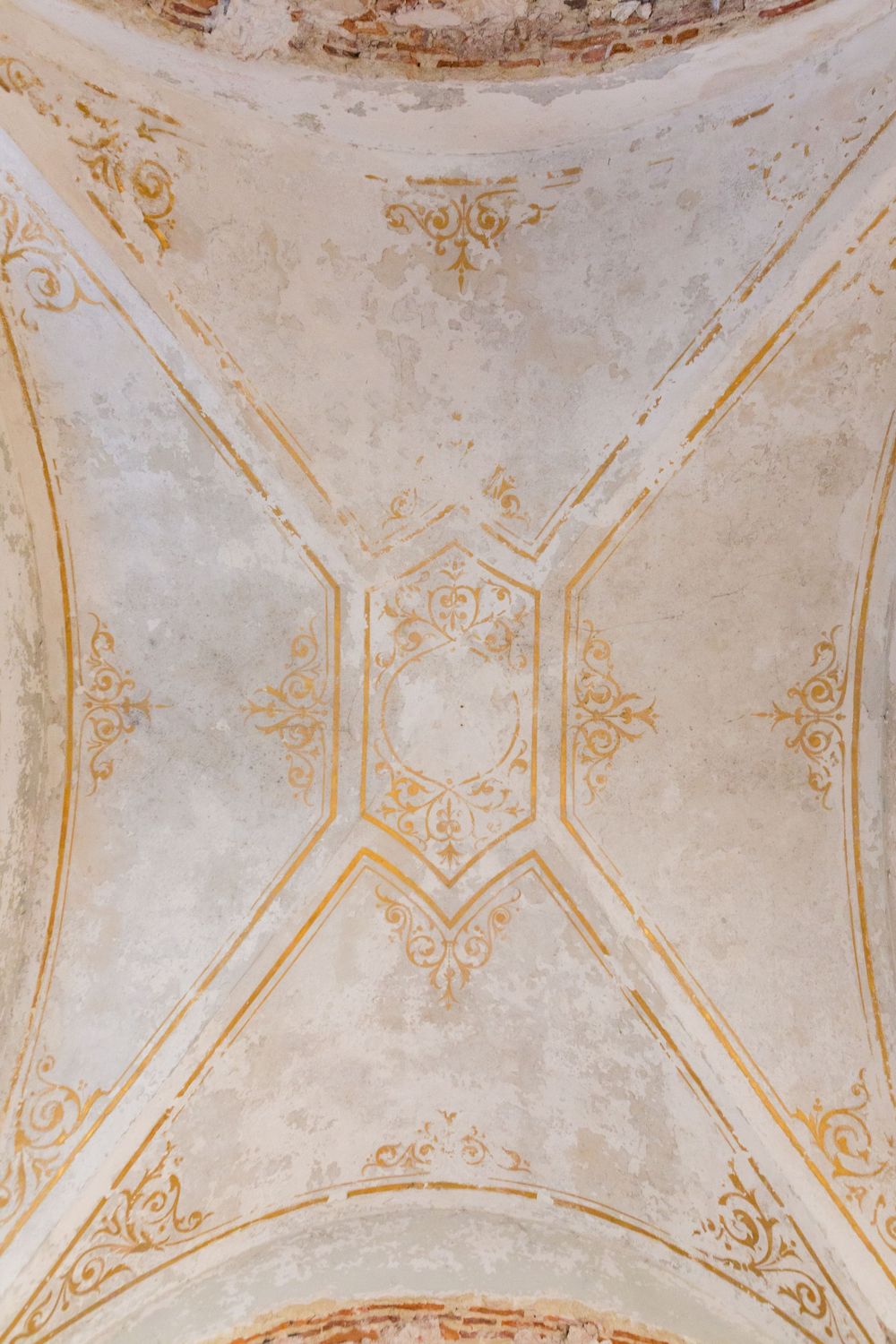 Ornate white and gold decorative ceiling with intricate floral patterns and geometric designs in a historic building.