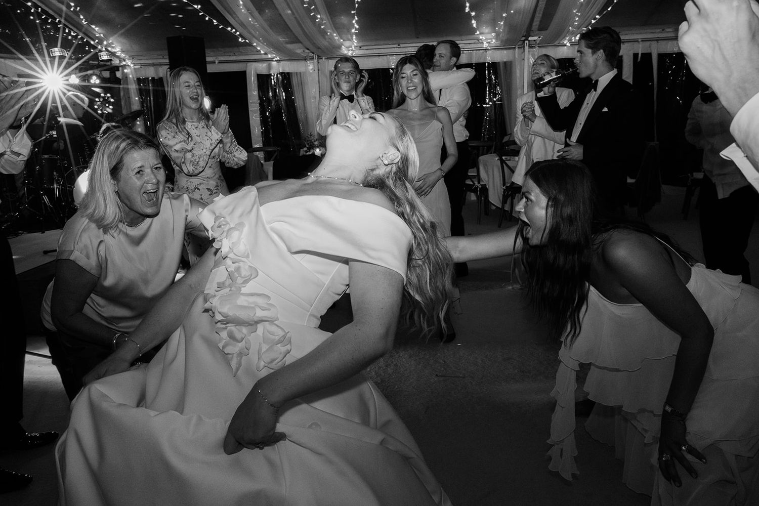 Wedding guests dance and celebrate on a dimly lit dance floor during an evening reception party.