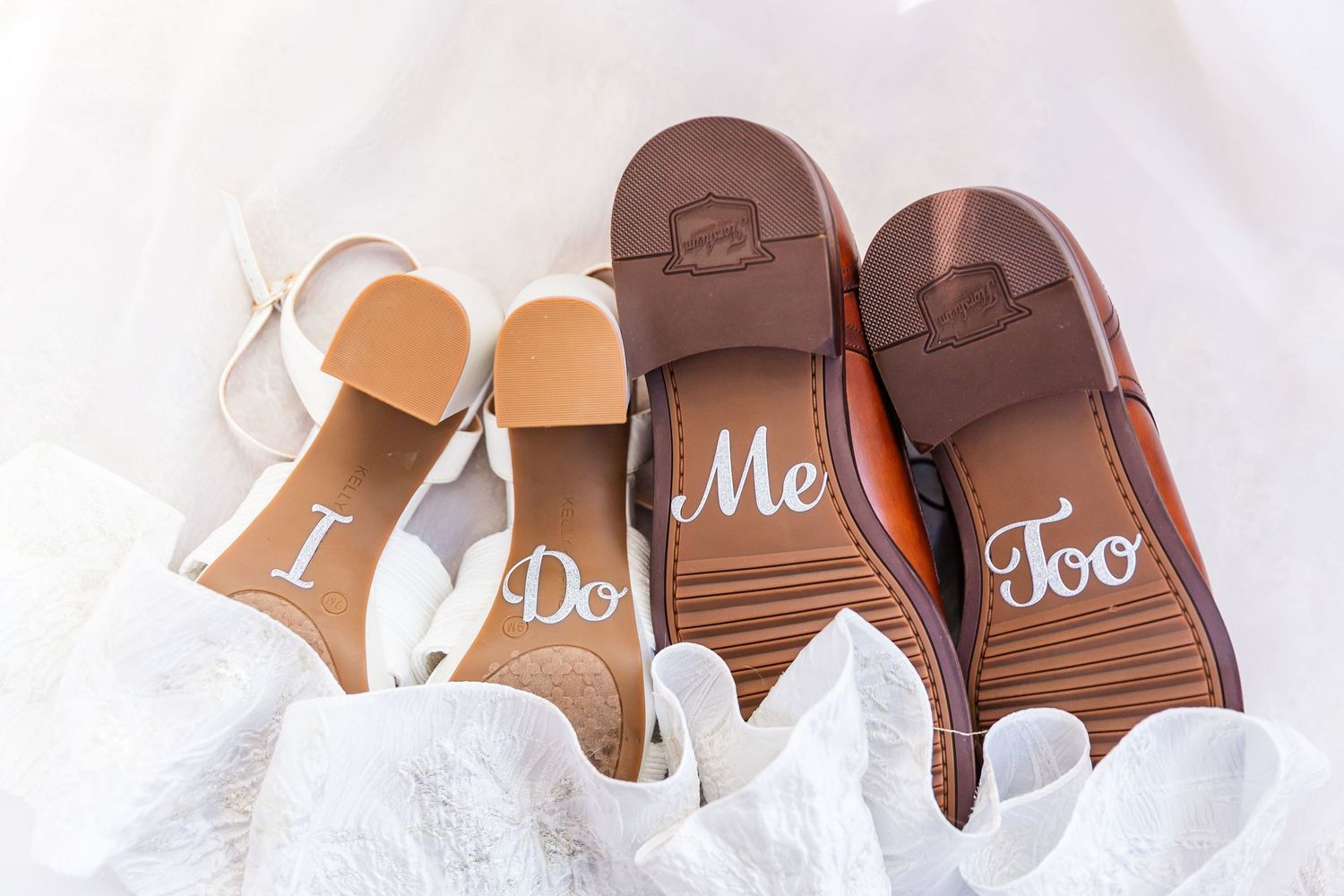 White and brown wedding shoes arranged with decorative 'I Do' text displayed on their soles.
