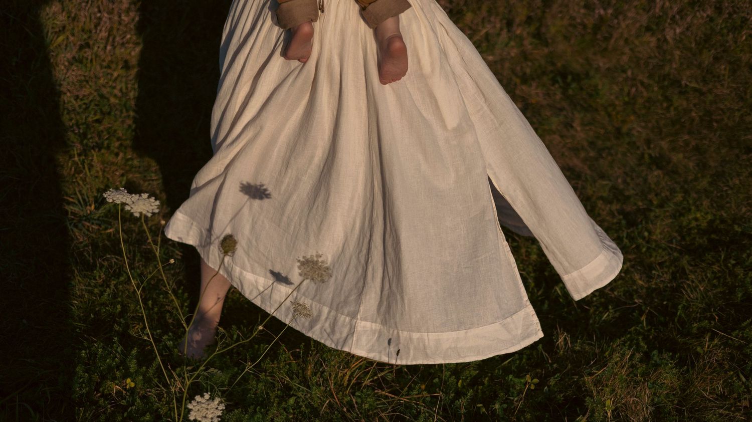 A white vintage-style dress flows gracefully in a series of spinning motion shots against a dark forest background.