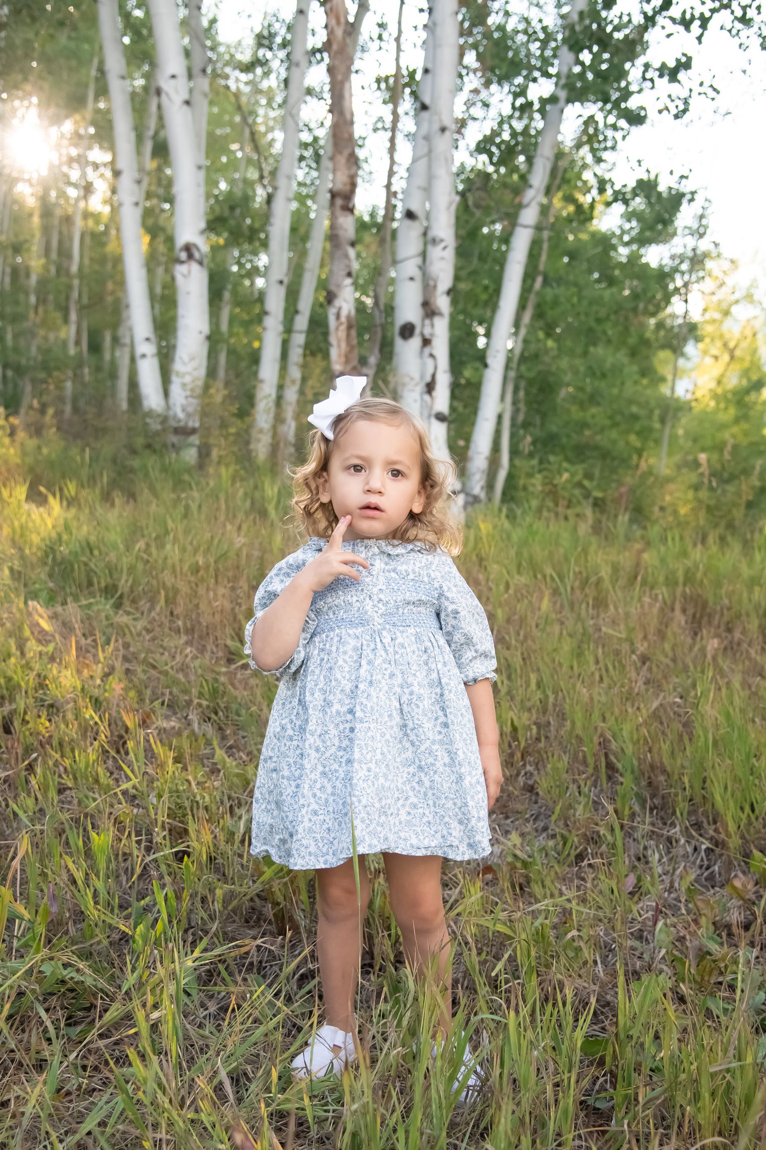 Cute moody photo of a whimsical girl in a dress standing with aspen trees behind her for family photos in Vail Colorado