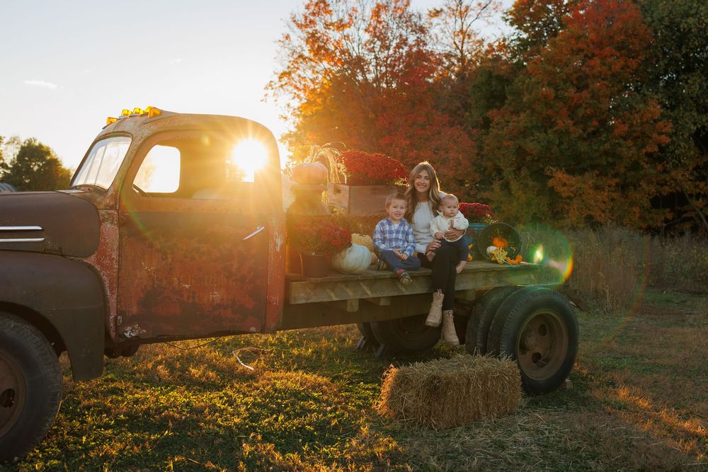 Golden sunset illuminates a rustic pickup truck parked in an autumn field with warm glowing light.