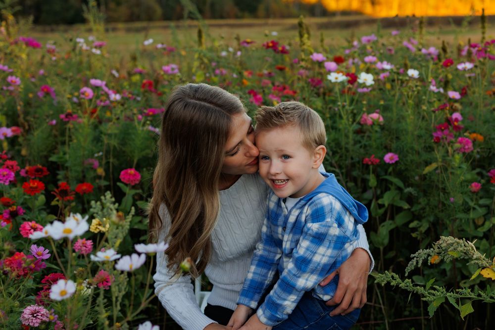 Family enjoying tender moments together in a vibrant flower garden at sunset.
