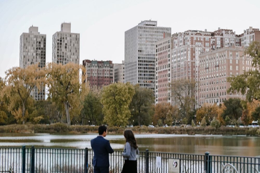 People walk along the Jacqueline Kennedy Onassis Reservoir path in Central Park with Upper East Side buildings in background.