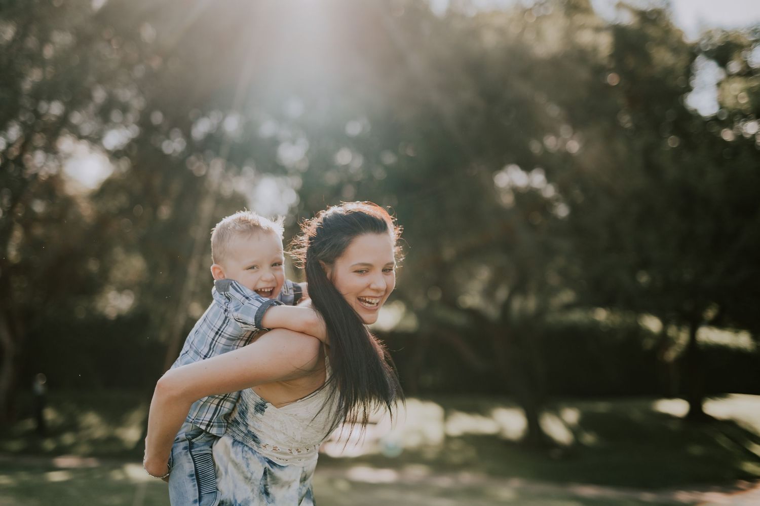 A joyful piggyback ride in a sunlit park during golden hour, creating a heartwarming outdoor moment.