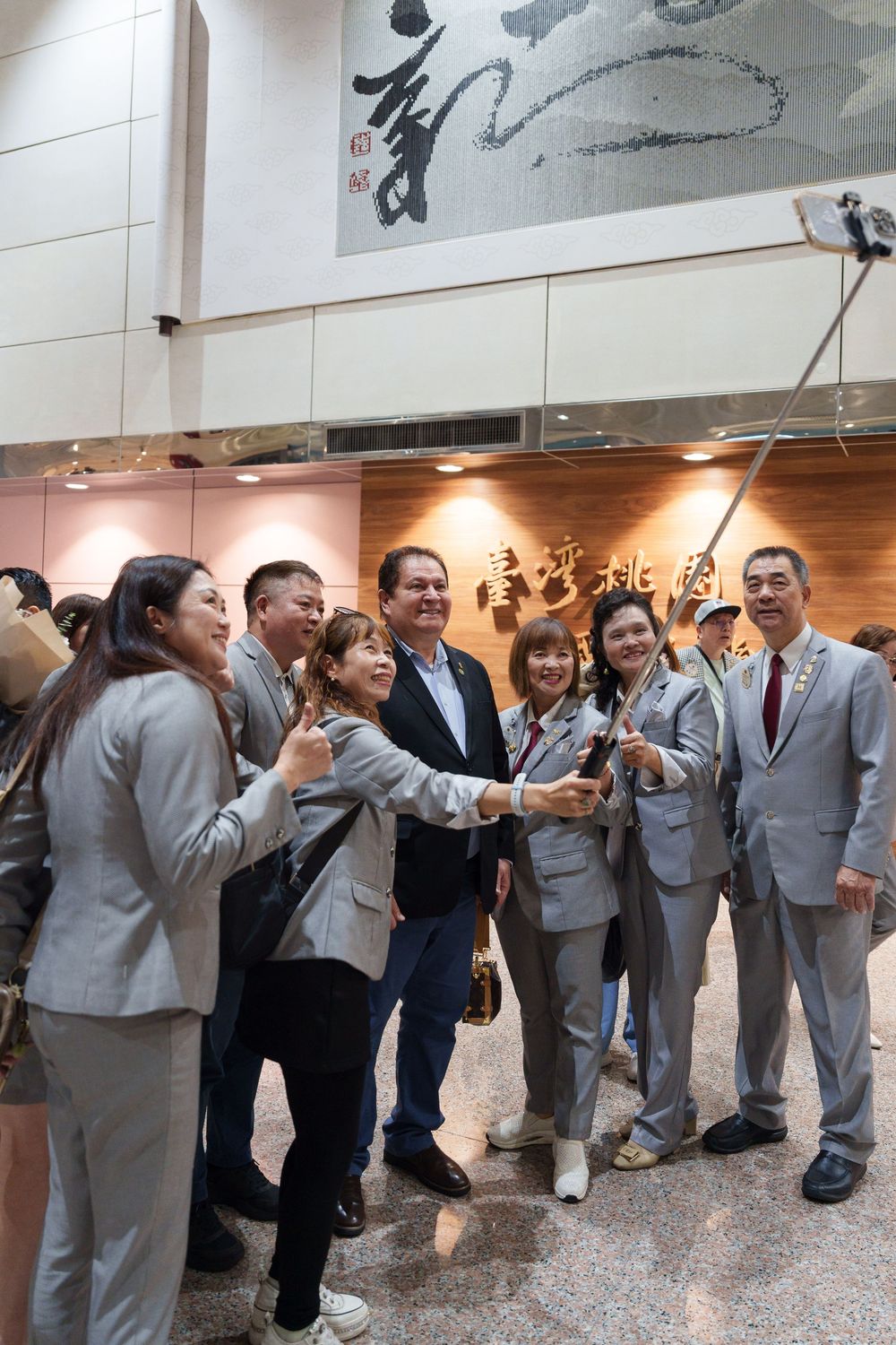 A line of people in gray suits and formal attire standing in an indoor hallway.