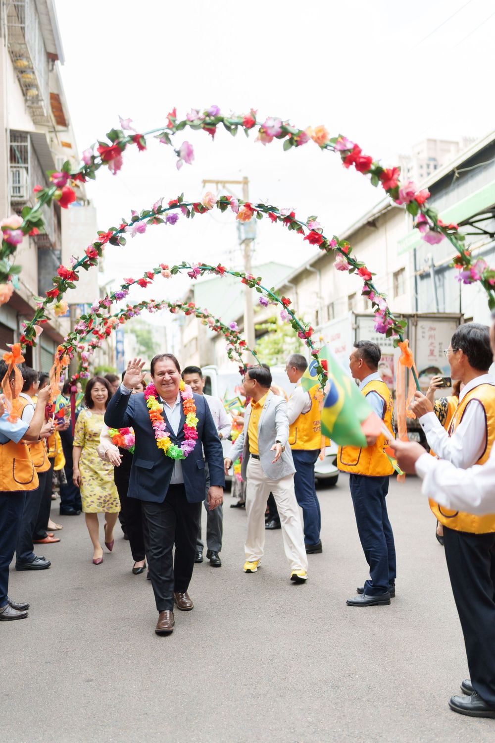 People celebrating under decorative floral arches at an outdoor festival or gathering.
