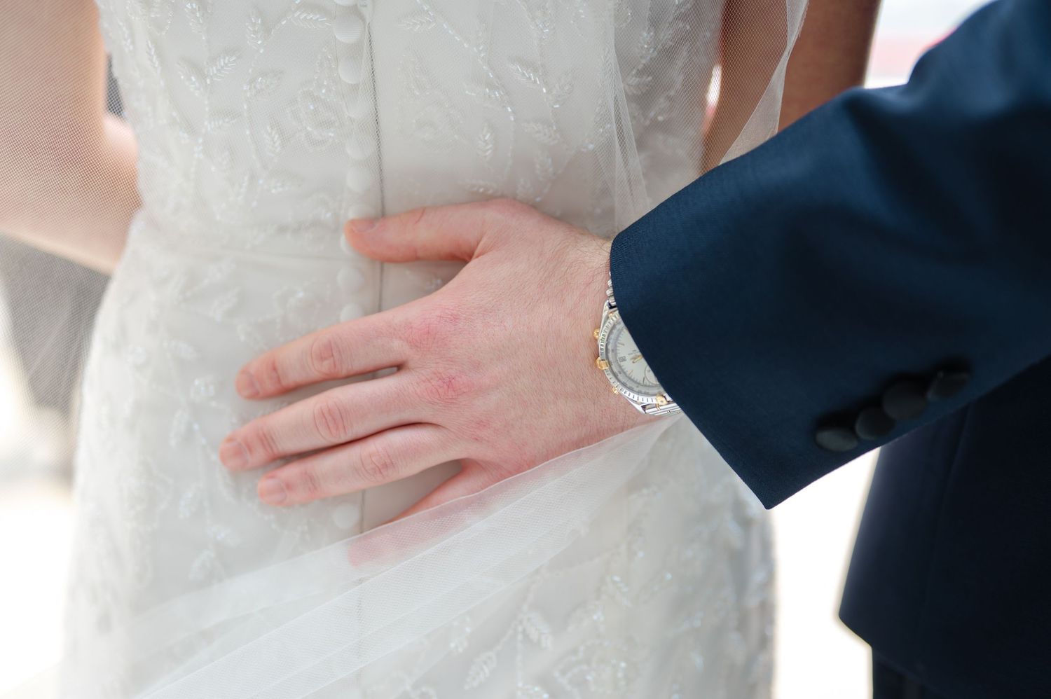 Close-up detail shots of a couple's hands and white wedding dress fabric during romantic wedding photography.