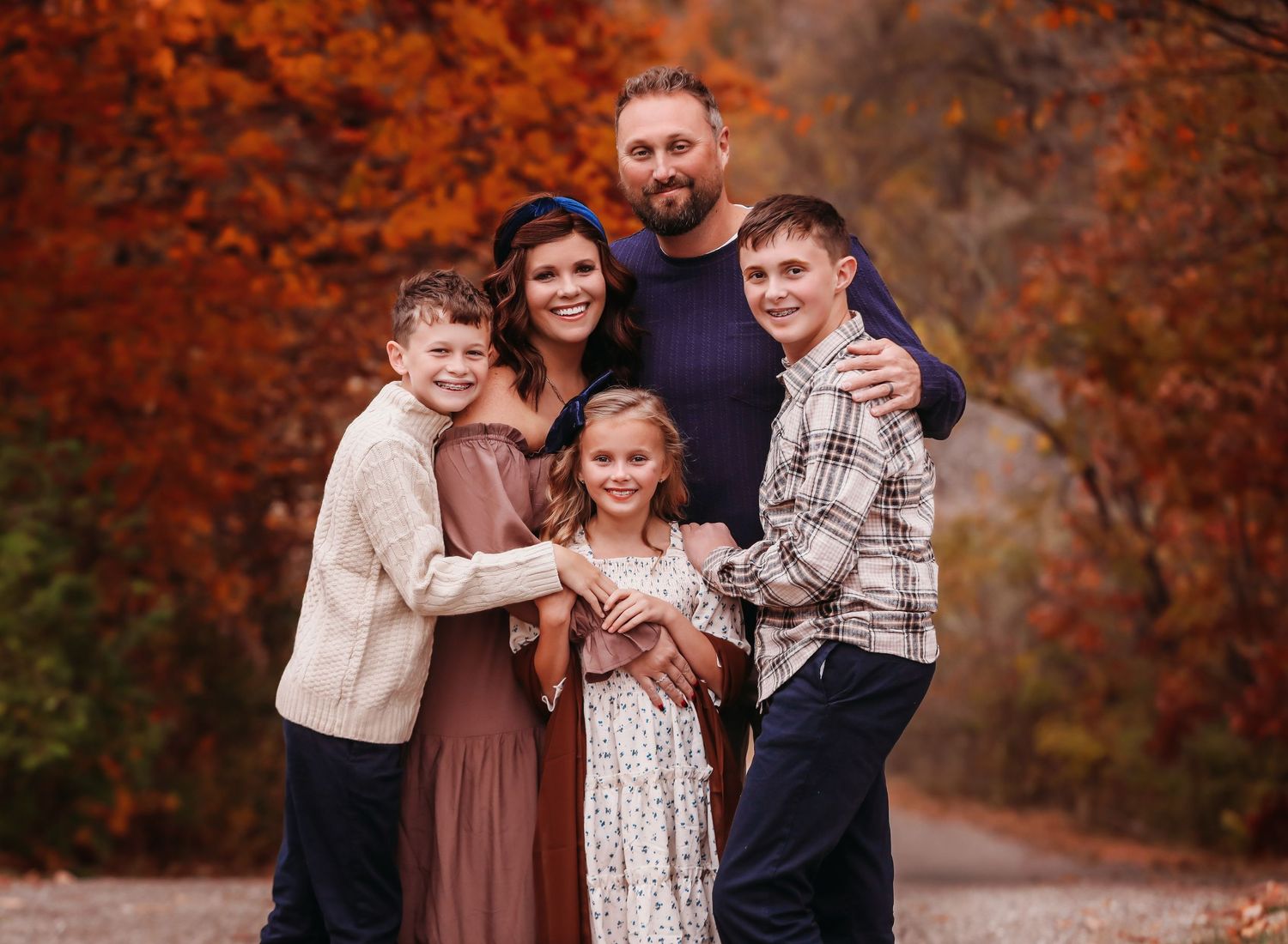 Family portrait with autumn foliage creating a vibrant orange backdrop.