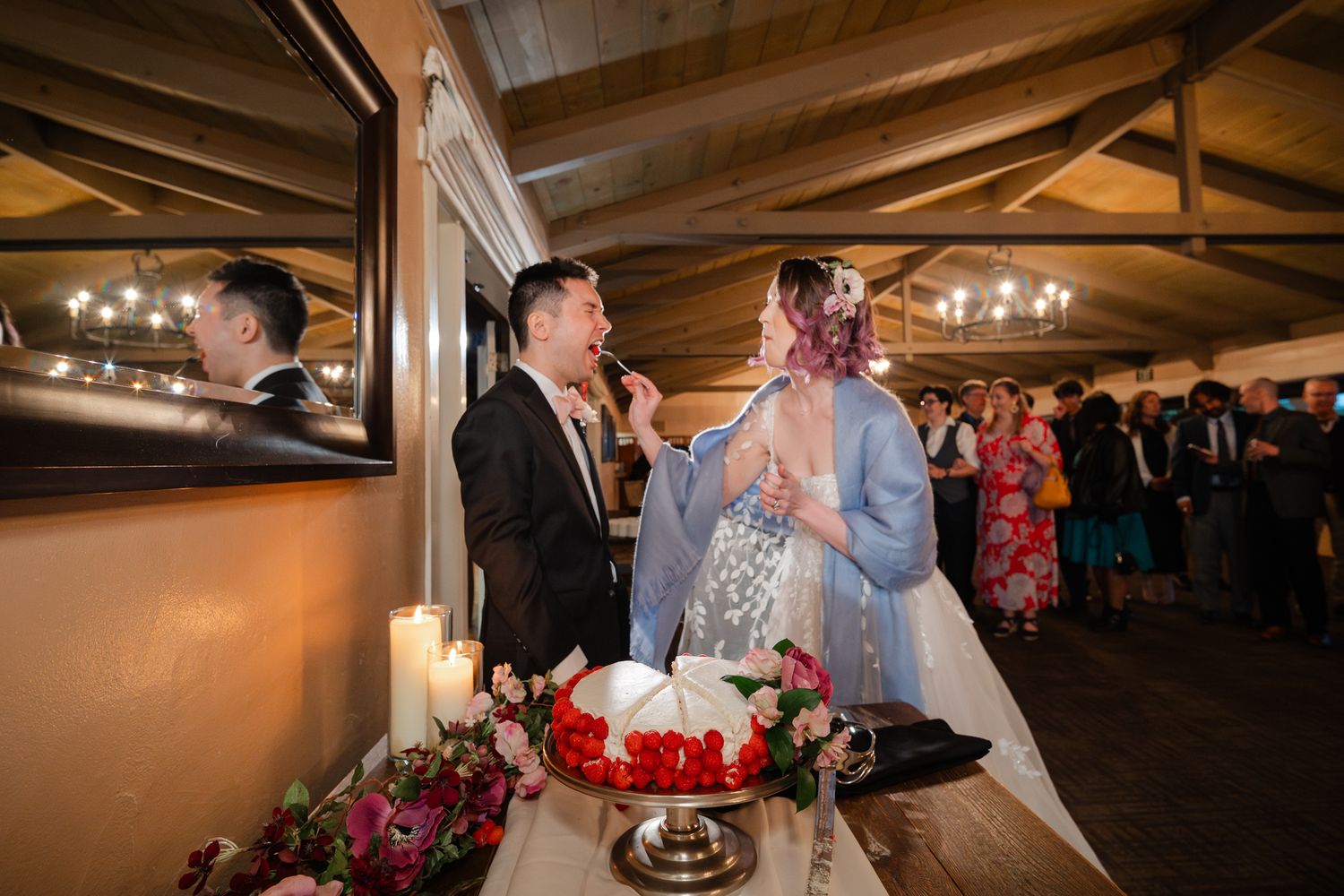 Wedding guests enjoy dancing and celebrating together on a rustic wooden dance floor under warm lighting.