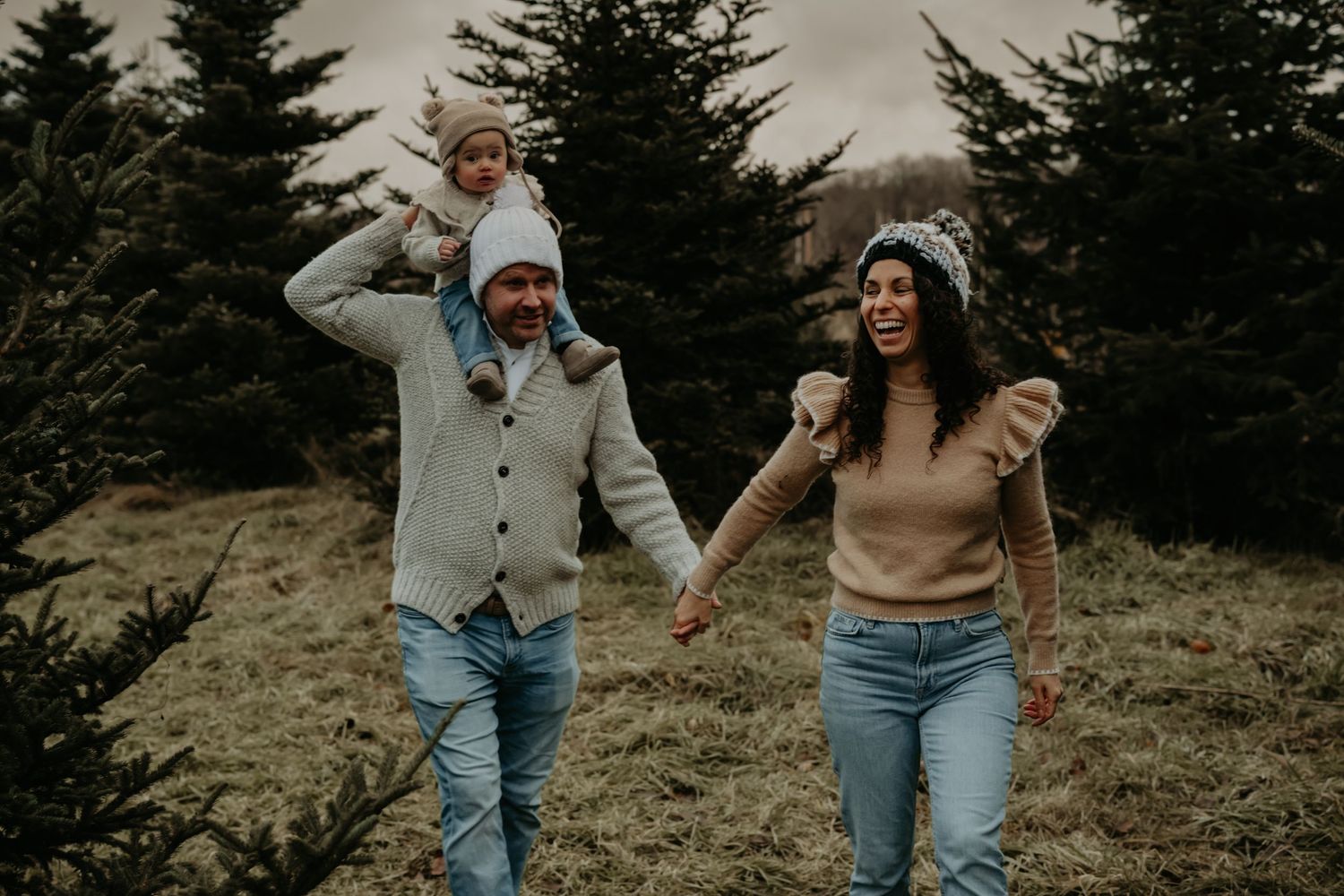 A family walking together through evergreen trees on a misty mountaintop path.